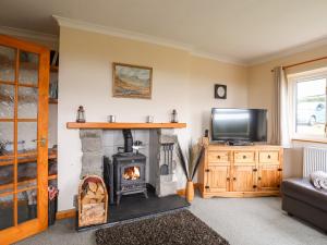 a living room with a fireplace and a tv at Pen Y Garth in Pwllheli