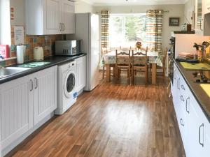 a kitchen with white cabinets and a wooden floor at Kestral in Welney