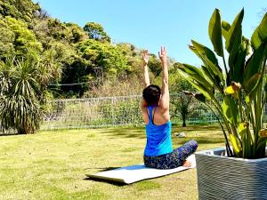 a woman doing yoga on a mat in a yard at 一棟貸別荘! Ohama Beach House & BBQ! 大浜海水浴場まで徒歩10分! Pets welcome! in Shimoda