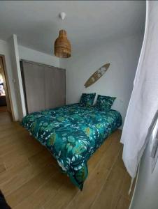 een slaapkamer met een bed met een groen dekbed bij Maison au calme avec piscine in Carcans