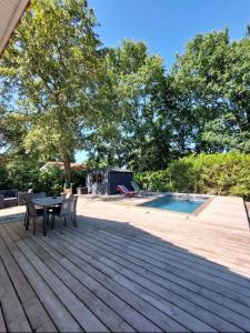 eine Terrasse mit einem Tisch und Stühlen neben einem Pool in der Unterkunft Maison au calme avec piscine in Carcans