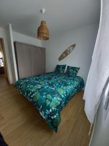 sypialnia z łóżkiem z zieloną kołdrą w obiekcie Maison au calme avec piscine w mieście Carcans