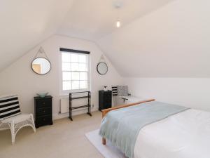 a white bedroom with a bed and a window at Bayview Loft in Weymouth