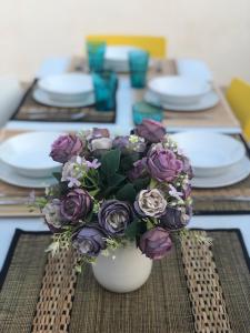 einen Tisch mit einer weißen Vase mit lila Blumen darauf in der Unterkunft Motorhome beach house in San José