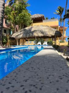 a resort with a swimming pool with a thatch roof at Villas Chiara Punta Cana in Punta Cana