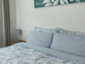 Cama con sábanas y almohadas azules y blancas en 16 Dean Court, en Lydney
