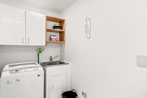 a kitchen with a washing machine and a sink at Relax on Snowberry - Wanaka Holiday Home in Wanaka +15 photos