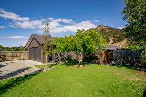 a yard with a house and a tree at Relax on Snowberry - Wanaka Holiday Home in Wanaka