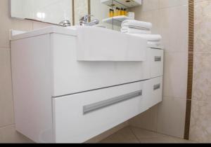a white bathroom with a sink and a mirror at Apartmani i sobe Centar Bugojno in Bugojno