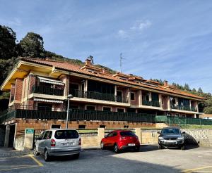un edificio con tres coches estacionados en un estacionamiento en Villa Mercedes - 17001, en Santoña