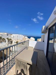 een balkon met een tafel en uitzicht op de oceaan bij Broadway By The Sea in St Paul's Bay