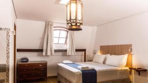 a bedroom with a bed and a window and a chandelier at Hotel Chalet Monet - Granja Vianna in Cotia