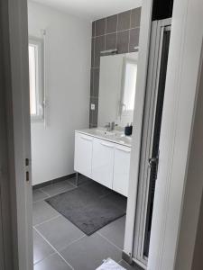 Baño blanco con lavabo y espejo en Belle maison neuve à 5 mn de la plage, en Colleville-Montgomery
