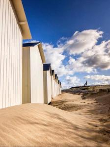 um edifício ao lado de uma praia arenosa em Belle maison neuve à 5 mn de la plage em Colleville-Montgomery