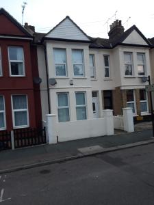 una casa blanca con una valla en una calle en B&T Pleasure Homes - Southend, en Southend-on-Sea