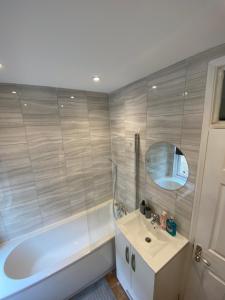 La salle de bains est pourvue d'une baignoire, d'un lavabo et d'un miroir. dans l'établissement B&T Pleasure Homes - Southend, à Southend-on-Sea