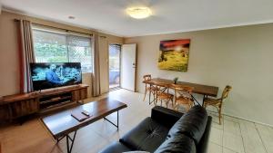 uma sala de estar com um sofá e uma televisão de ecrã plano em Stroll to the City Center in Minutes em Toowoomba