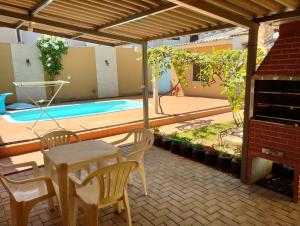 a patio with a table and chairs and a swimming pool at Casa com piscina próximo à Avenida das Cataratas in Foz do Iguaçu