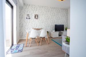 een eetkamer met een tafel en twee witte stoelen bij Olhos d'Água - Penthouse in Nazaré