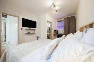 a bedroom with a white bed with a television on the wall at Hygge Rooms Split in Split +25 photos