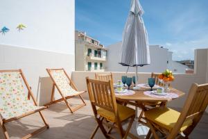 een tafel en stoelen op een balkon met een parasol bij Olhos d'Água - Penthouse in Nazaré