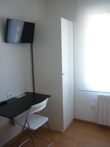 a room with a black desk and a white chair at Pensión-Albergue Puente Ribeira in Sarria