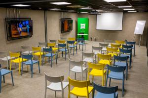 a room with yellow and blue chairs and a screen at ibis styles Lima San Isidro in Lima