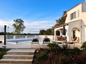 a house with a patio with chairs and a pool at Villa Joanna in Son Bou