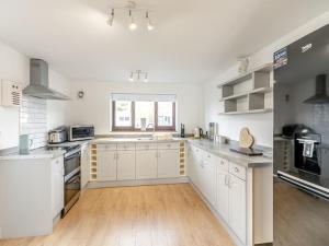a large kitchen with white cabinets and a wooden floor at Stunning Three Bed Cottage - Cottage 3 in Doncaster