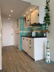 a kitchen with white cabinets and blue tile at O som das ondas - vista soberba de mar in Sesimbra