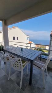 a wooden table and chairs on a balcony with the ocean at Apartment Sušanj Ravni with sea view in Ravni