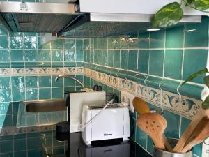 a kitchen with green tiles on the wall at O som das ondas - vista soberba de mar in Sesimbra