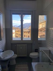 La salle de bains est pourvue d'un lavabo, de toilettes et de 2 fenêtres. dans l'établissement Holly's House apartment, à Alzano Lombardo