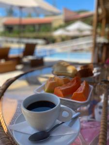 a table with a cup of coffee and a plate of fruit at Duplex Solar Água in Pipa