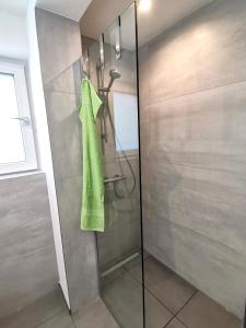 a shower with a green towel on a glass door at Moderne Ferienwohnung Gartenblick in Amtzell