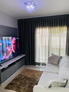 a living room with a couch and a flat screen tv at Apartamento próximo da Lucas in Atibaia
