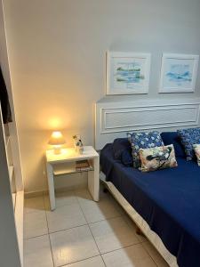 1 dormitorio con 1 cama y 1 mesa con lámpara en Ilha da Madeira Resort Riviera de São Lourenço SP en Bertioga