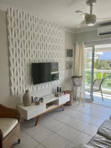 sala de estar con TV de pantalla plana en la pared en Ilha da Madeira Resort Riviera de São Lourenço SP en Bertioga