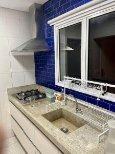 un comptoir de cuisine avec un évier et une fenêtre dans l'établissement Ilha da Madeira Resort Riviera de São Lourenço SP, à Bertioga