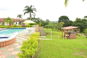 un patio trasero con piscina y parque infantil en FINCA HOTEL TRADICION CAFETERA, en Quimbaya