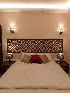 Relax Guest House في السادس من أكتوبر: غرفة نوم بسرير ابيض كبير ومصباحين