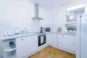 a white kitchen with white cabinets and a window at Spacious 4 Bed Home With Parking in Manchester
