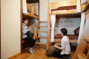 two people sitting in a room with bunk beds at tabi-shiro in Matsumoto