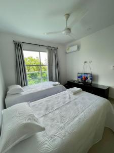 a bedroom with two white beds and a window at CIC APARTAMENTOS cerca UNICOR IMAT in Montería