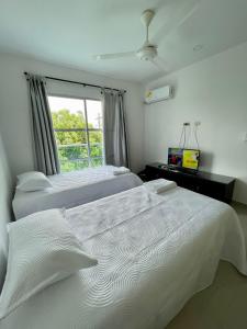 Duas camas brancas num quarto com uma janela em CIC APARTAMENTOS cerca UNICOR IMAT em Montería