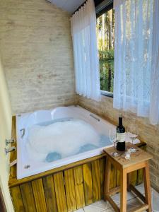 a jacuzzi tub with a table and wine glasses at Chalé Recanto dos Pinheiros in Monte Verde