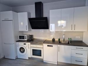kuchnia z białymi szafkami, zlewem i kuchenką mikrofalową w obiekcie Apartamento mi currilla w mieście Sanlúcar de Barrameda