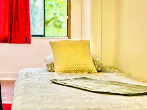 a bed with a yellow pillow and a window at Fortune Guest house in Lisbon