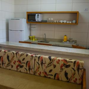 a kitchen with a counter and a refrigerator and a couch at Pousada Ilha Vitoria in Ubatuba