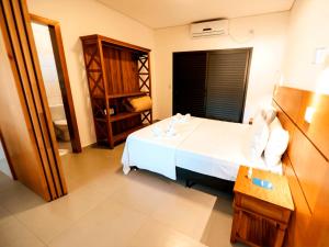 a bedroom with a white bed and a chair at Pousada Ilha Vitoria in Ubatuba